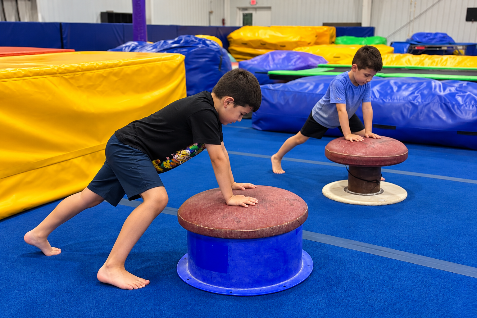 Two boys practicing with low round gymnastics equipment