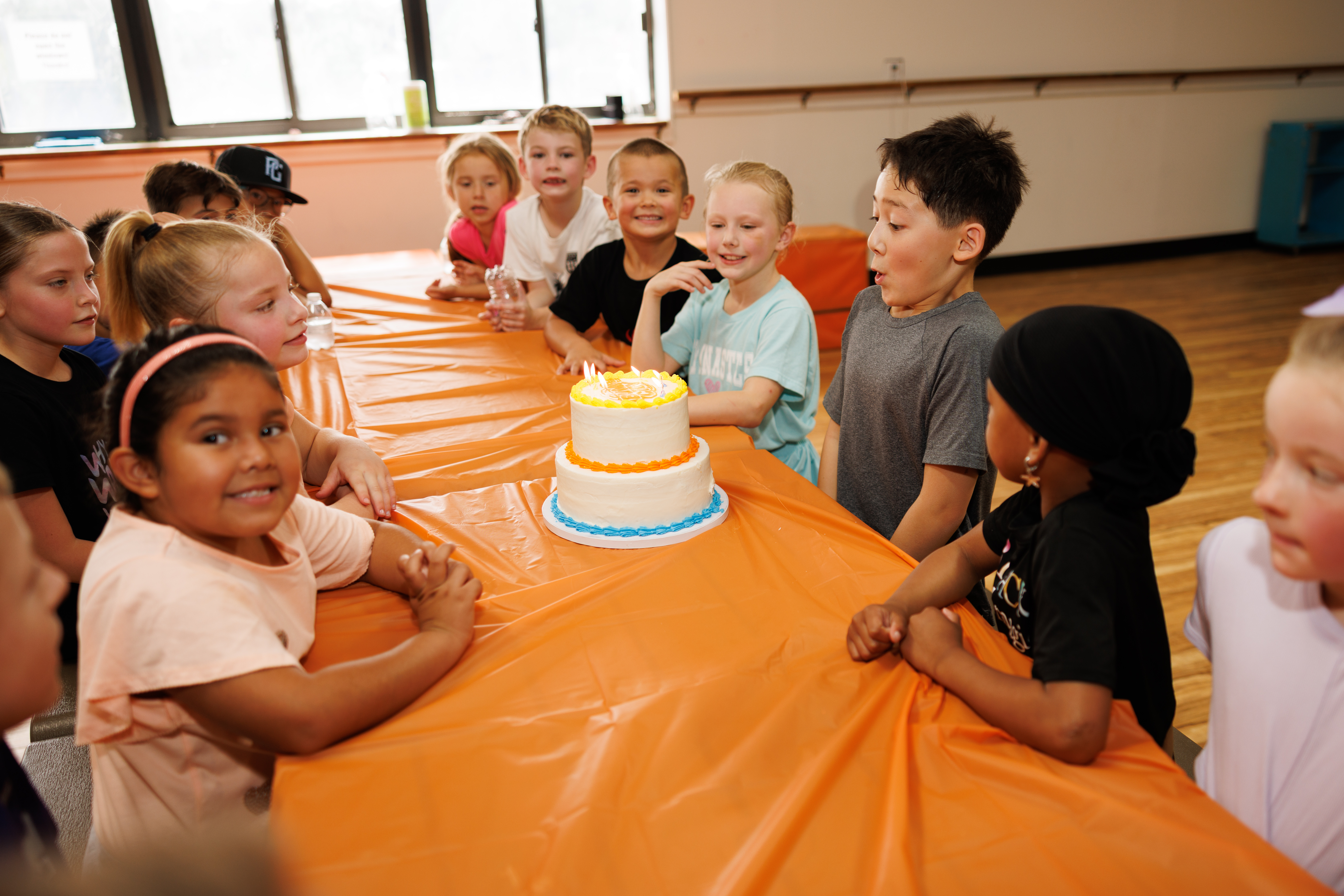 Children gathered around a birthday cake in the party room