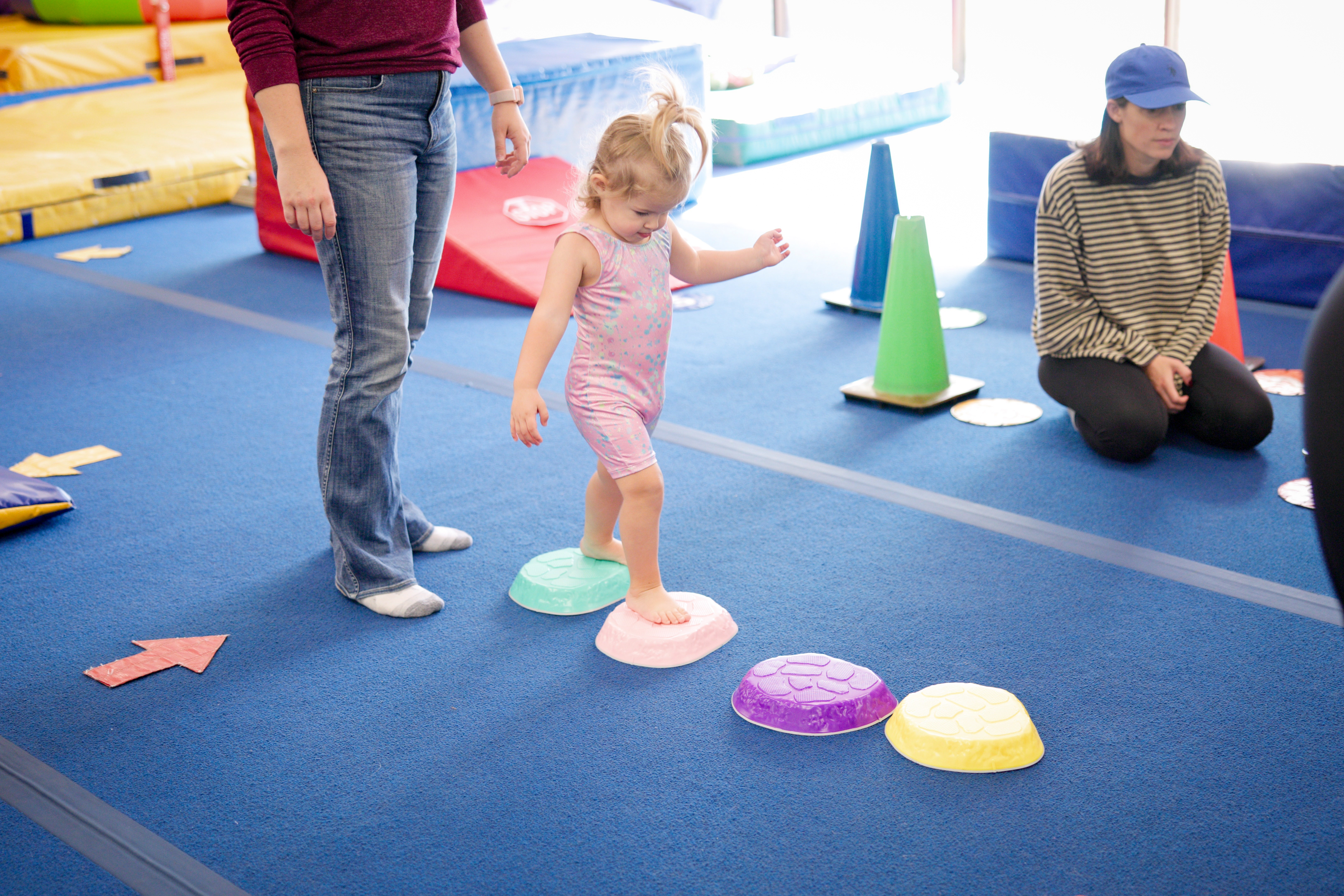 Toddler walking across low stepping stones with an adult nearby